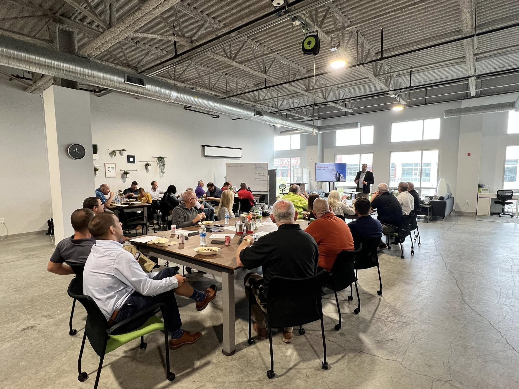 Image of professionals sitting at tables learning from a presenter.